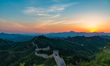 the great wall, Beijing, chinatravel, Sunset lights up the Great Wall winding over green hills and watchtowers at dusk.
