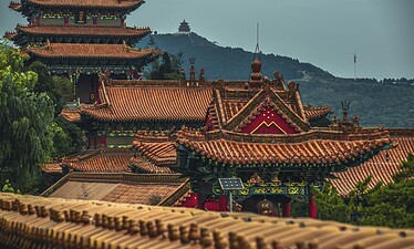 Chongqing Huguang Guild Hall, China Travel, Traditional Chinese temple complex with red tiled roofs and ornate carvings, set against a hilly landscape.