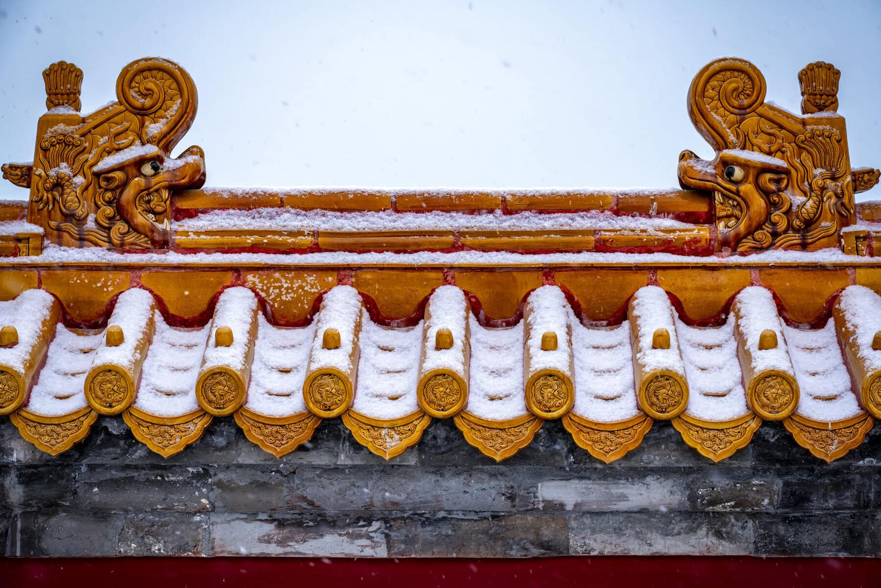 the forbidden city, snow view, beijing, chinatravel, Orange ceramic roof tiles with ornate dragon-head finials, lightly dusted with snow against a pale sky.