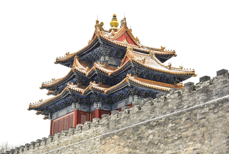 Ornate multi-tiered Chinese temple roof with gold accents and upturned eaves atop a stone wall.