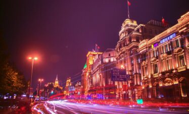 shanghai, china, china tour, Nighttime city street with illuminated historic buildings and neon signs; long exposure light trails from passing cars create red and white streaks.