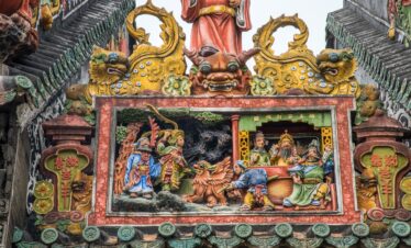 Chen Clan Ancestral Hall, guangzhou, china, chinatrip, Colorful Chinese temple facade with gold dragon heads and a detailed relief showing figures and a beast in a red frame at the center of the scene example of traditional temple art.