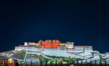 Potala Palace Tibet, china, china tour, Night view of the Potala Palace in Lhasa, with white and red tiered walls illuminated against a dark sky.