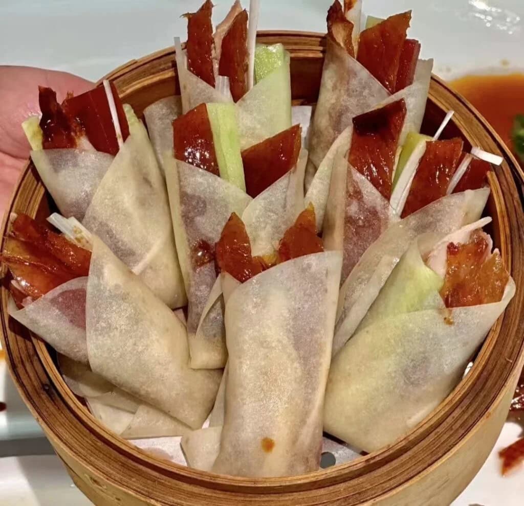 beijing duck, china tour, Basket of translucent spring rolls filled with char siu pork and vegetables, arranged upright in a wooden steamer basket.