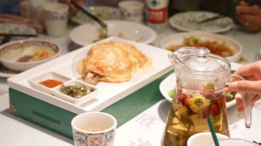 chinese food, china tour, Roasted chicken on a white tray with small condiment dishes, surrounded by bowls on a busy dining table.