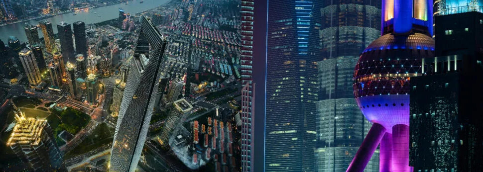 Shanghai City Tours, china tour, Nighttime city skyline with illuminated skyscrapers and brightly lit streets viewed from above, neon reflections on glass façades.
