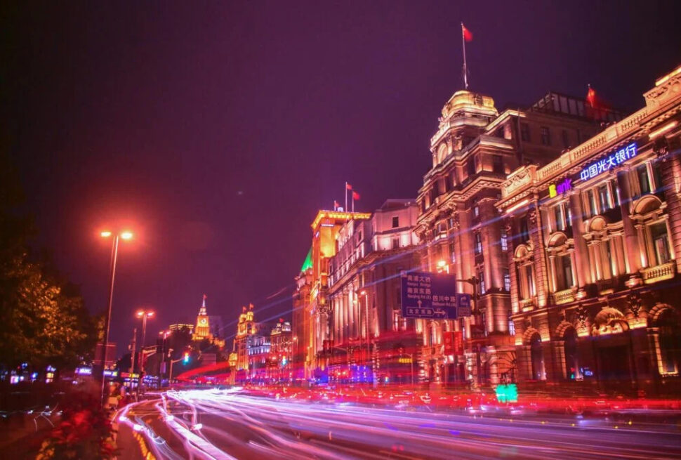 shanghai city tour, china, china tour, Nighttime city street with ornate, illuminated buildings and red light trails from moving cars.