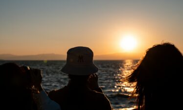 8-Day Yunnan Culinary Cultural Adventure, china, china tour, Silhouetted people watching a sunset over the ocean, with the sun low on the horizon and reflections on the water.
