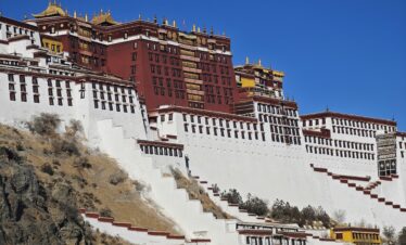 Potala Palace Tibet, china, china tour, Potala Palace in Lhasa perched on a hillside with white walls, red and gold buildings, and a clear blue sky above.