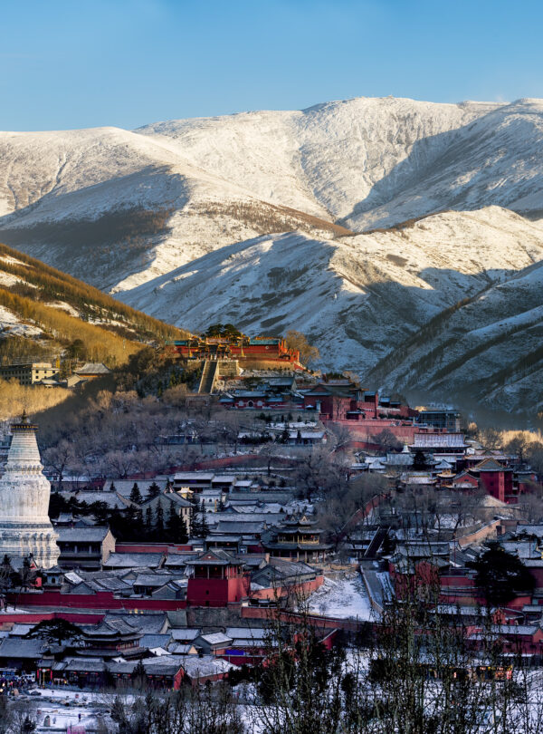 Mount Wutai, shanxi, china, china tour, Snowy mountain town with red buildings and a white pagoda in the foreground, snow-covered slopes in the background under a blue sky.