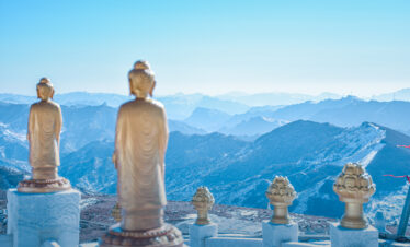 Tayuan Temple, wutai retreat, shanxi, china, china tour, Golden Buddha statues on white pedestals along a viewing platform with blue, misty mountains in the background