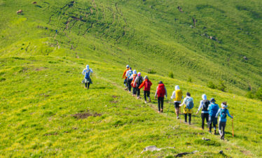 Mount Wutai, shanxi, china, china tour, A line of hikers with backpacks walking along a grassy hillside trail in a green valley.