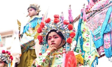 Chinese Lunar New Year, southern china, chinatrip, Young girl in a colorful traditional festival costume with an ornate headdress, preparing for a performance.