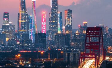 guangzhou, china, chinatrip, Guangzhou skyline at dusk with rainbow-lit Canton Tower, tall illuminated skyscrapers, and a curved red bridge over the Pearl River in the foreground.