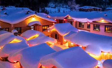 Enchanting Winter Wonderland: 3-Day Journey Through Harbin: China's Snow Kingdom, chinatrip, Snowy mountain village at night with warm orange lights glowing from windows and heavy snow on roofs under a starry blue sky.