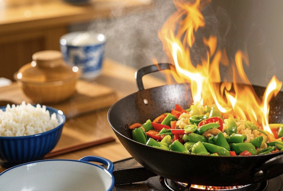 chinese food, china, chinaexplorertour, Stir-fry vegetables in a hot wok with flames, and blue-rimmed bowls of rice on the counter nearby.