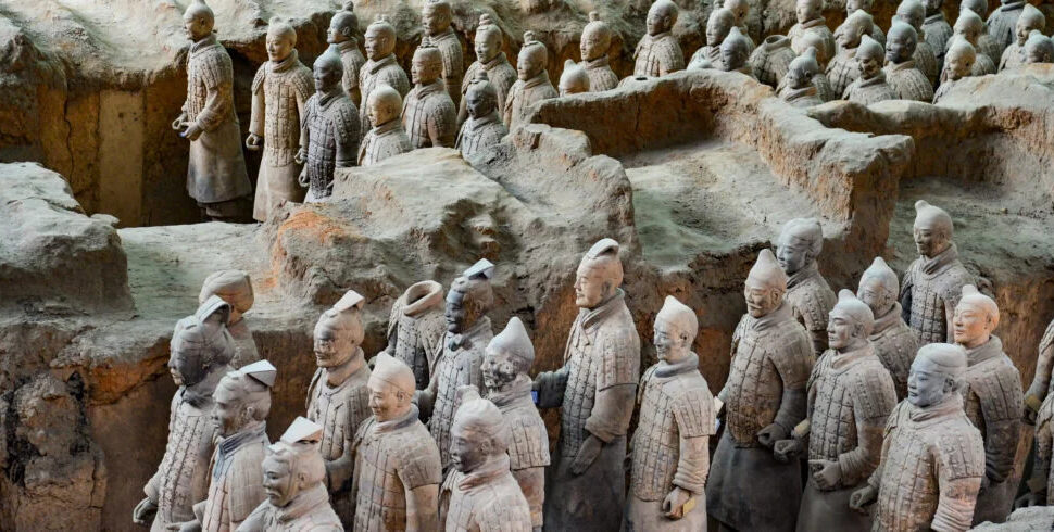 Terracotta Army museum. Xi'an. Chintravel, Rows of life-sized terracotta soldiers standing in excavated earthen pits, part of China’s Qin dynasty mausoleum.
