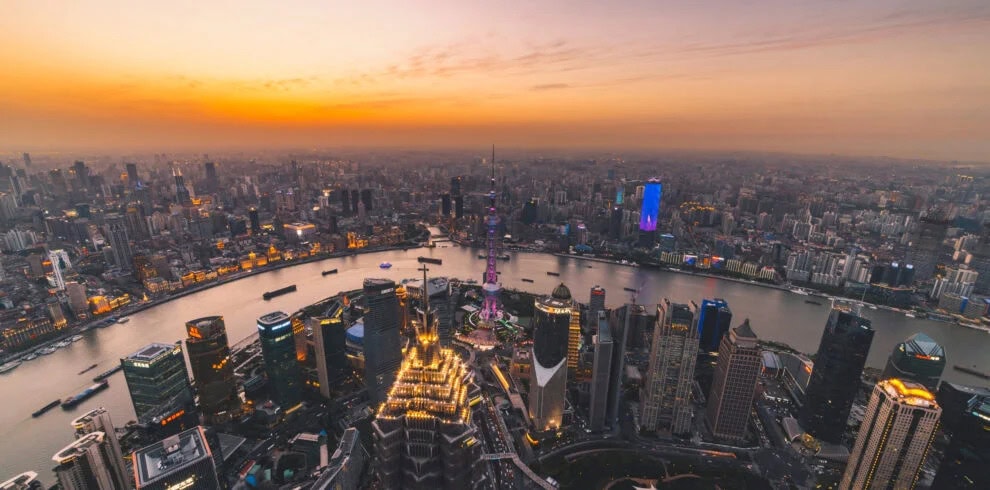 shanghai, the bund, chinatravel, Aerial view of Shanghai skyline at sunset, with the Huangpu River winding through tall illuminated skyscrapers.