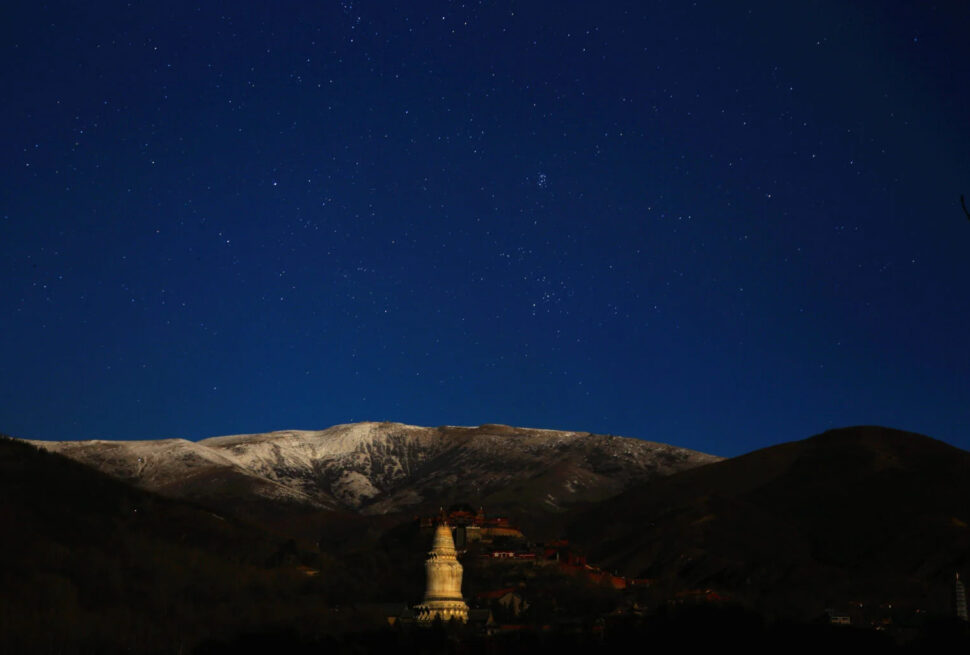 wutai mountain, wutai, chinatravel, Star-filled night sky over snow-capped mountains with a lit Buddhist stupa in the valley.