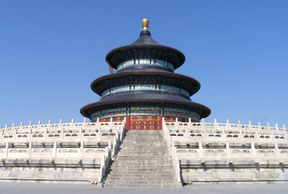 temple of heaven, beijing, chinatrip, Circular three-tiered blue-roofed temple on a raised platform with red doors, set against a clear blue sky.