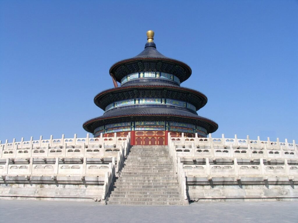 temple of heaven, beijing, chinatrip, Circular three-tiered blue-roofed temple on a raised platform with red doors, set against a clear blue sky.