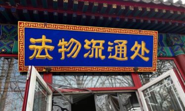 Yonghe Temple official Spiritual Gift Shop, beijing, chinatrip, Blue sign with gold Chinese characters mounted above an open doorway in a traditional Chinese building surface decorate with red trim and ornate frame.