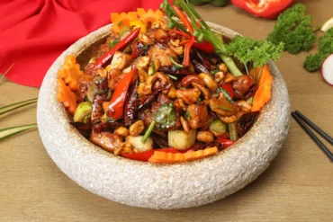 chinese food, chinatrip, Stir-fried vegetable and nut medley (cashews, peppers, carrots) served in a round stone mortar bowl with chopsticks nearby