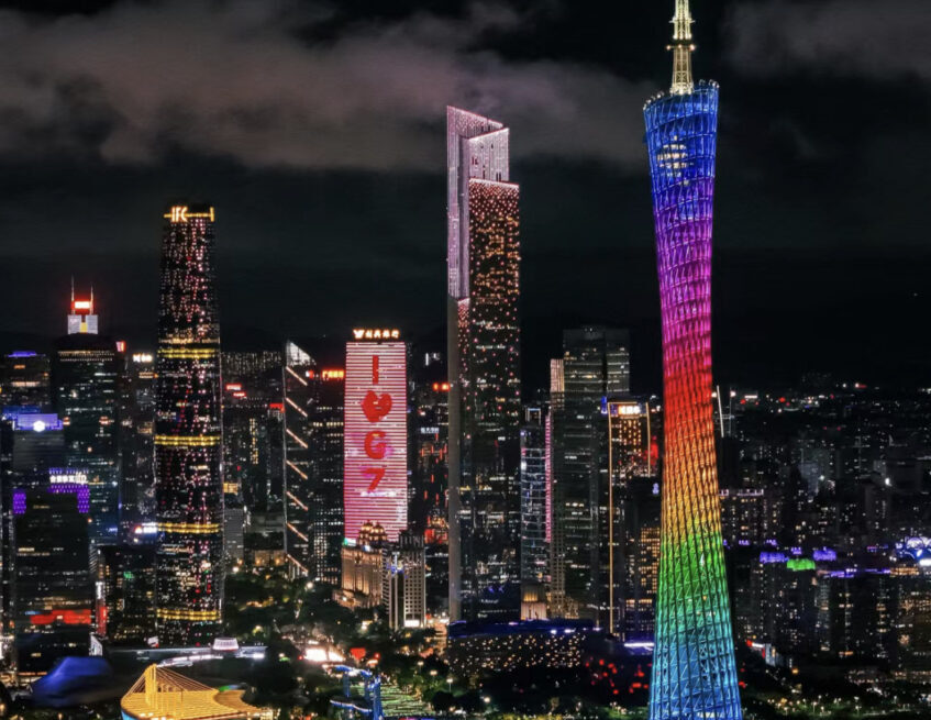 Guangzhou skyline at night featuring the Canton Tower lit in rainbow colors beside the river.