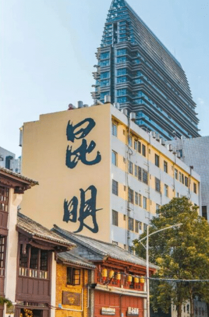 City street with traditional storefronts in the foreground, a beige building displaying two large black Chinese characters on its side, and a tall modern skyscraper in the background.