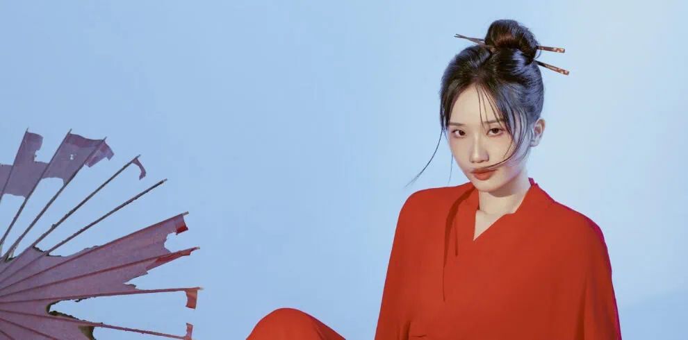 Hanfu,China Culture,Chinatour Portrait of a young woman in a red outfit against a light blue background, with a pink fan visible on the left side.