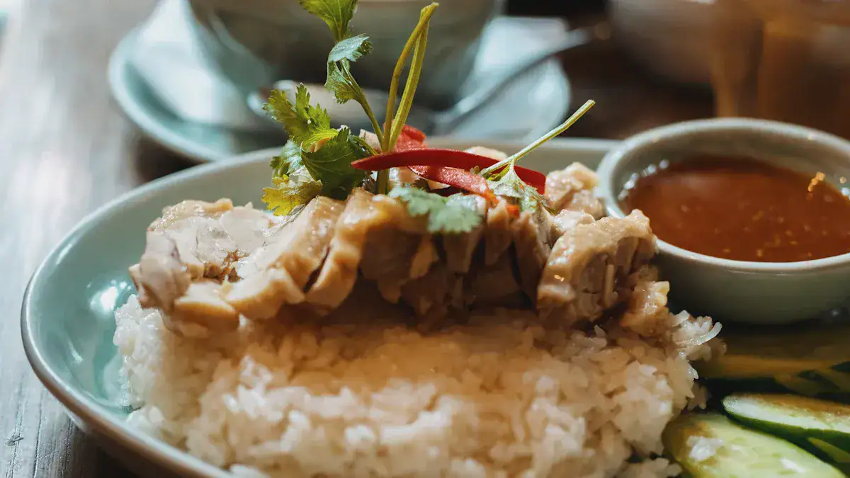 Plate of white rice topped with sliced chicken, cilantro, and a red chili, with a small bowl of sauce on the side.