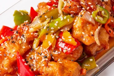 Stir-fried chicken with bell peppers, onions, and sesame seeds in a glossy sauce.