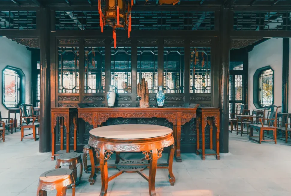 Best Vegetarian Restaurants,Humble Administrator's Garden,Chinatour Dark wood shrine room with an ornately carved altar, porcelain vases, and a round marble-topped table.