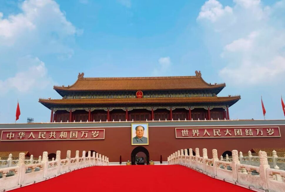 Tiananmen Gate in Beijing with Mao Zedong portrait, red banners, and a long red carpet leading to the entrance.