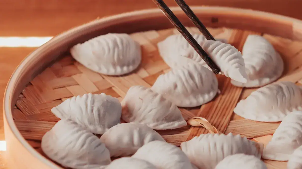 Dumplings arranged in a bamboo steamer, with chopsticks lifting one dumpling.