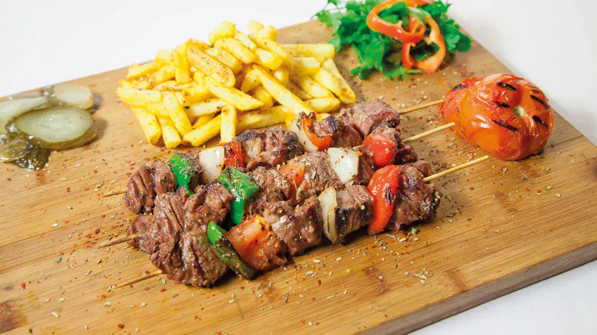 Beef kebab skewers with onions and peppers, served with fries and a grilled tomato on a wooden board
