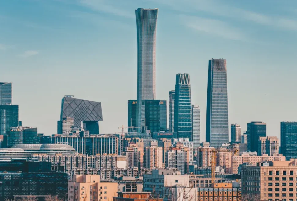 Modern city skyline with tall glass skyscrapers against a clear blue sky.