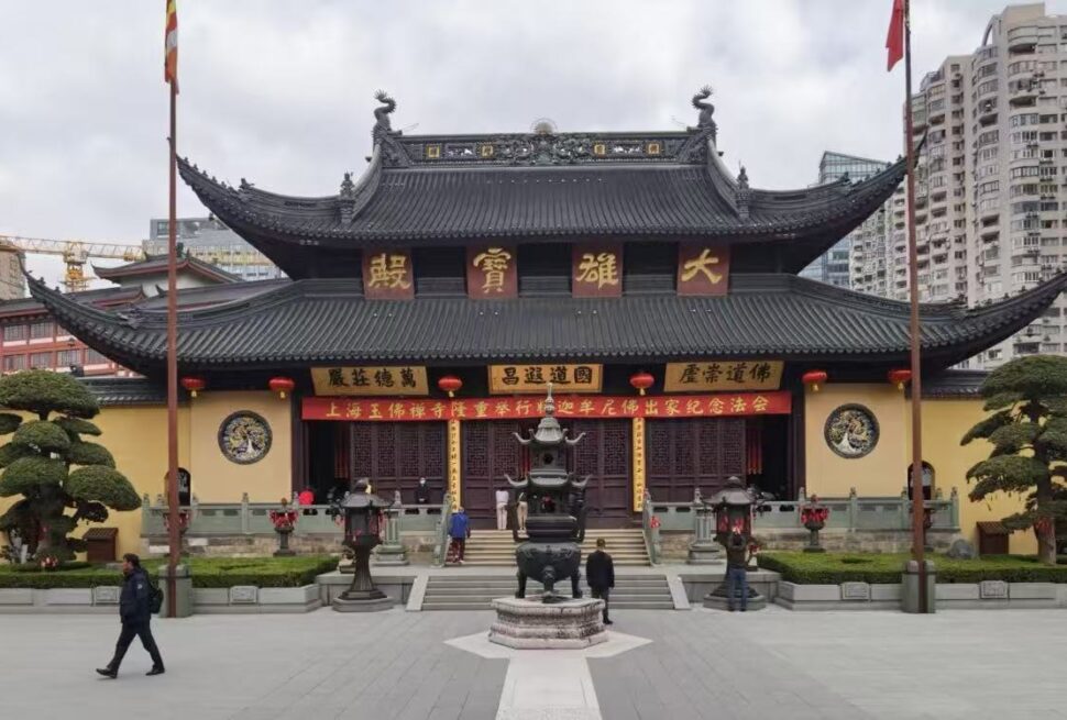 Shanghai Jade Buddha Temple,Shanghai,Chinatour Traditional Chinese temple with ornate curved roof and red lanterns in a courtyard, urban high-rises in the background.