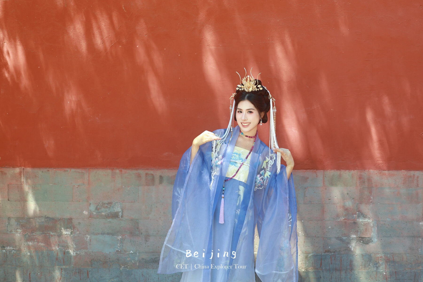 Hanfu photoshoot, Beijing, Imperial Ancestral Temple (Tai Miao), female, chinatravel, Woman in blue traditional Chinese attire with an ornate gold headpiece, posing against a red wall (Beijing travel image).
