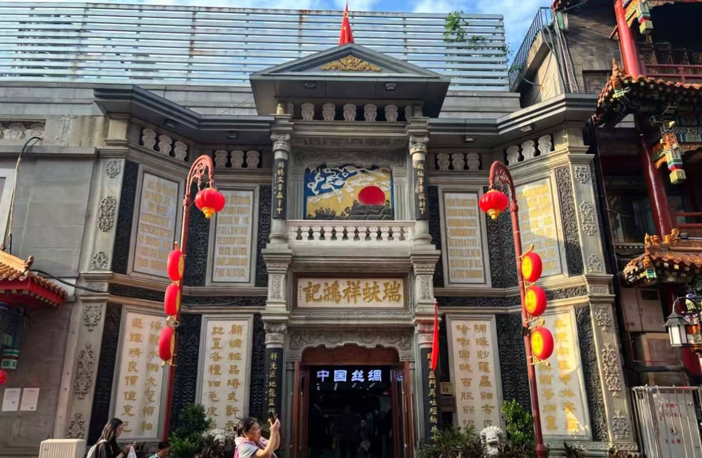 Dashilan Hutong,Beijing,Chinatour Ornate Chinese temple facade with gold inscriptions, stone columns, and red lanterns along the sides of a central doorway.
