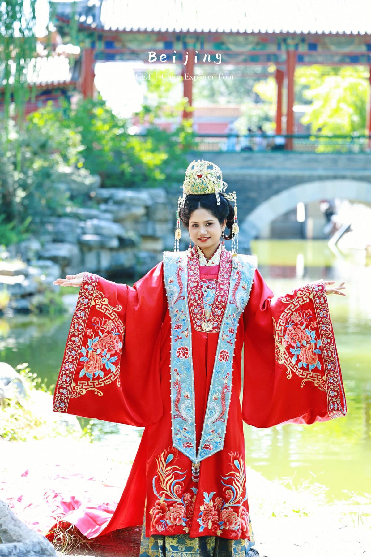 Hanfu photoshoot, zhongshan park, beijing, chinatravel, Woman in an elaborate red traditional Chinese ceremonial dress with a jeweled crown, standing with arms outstretched in a garden.