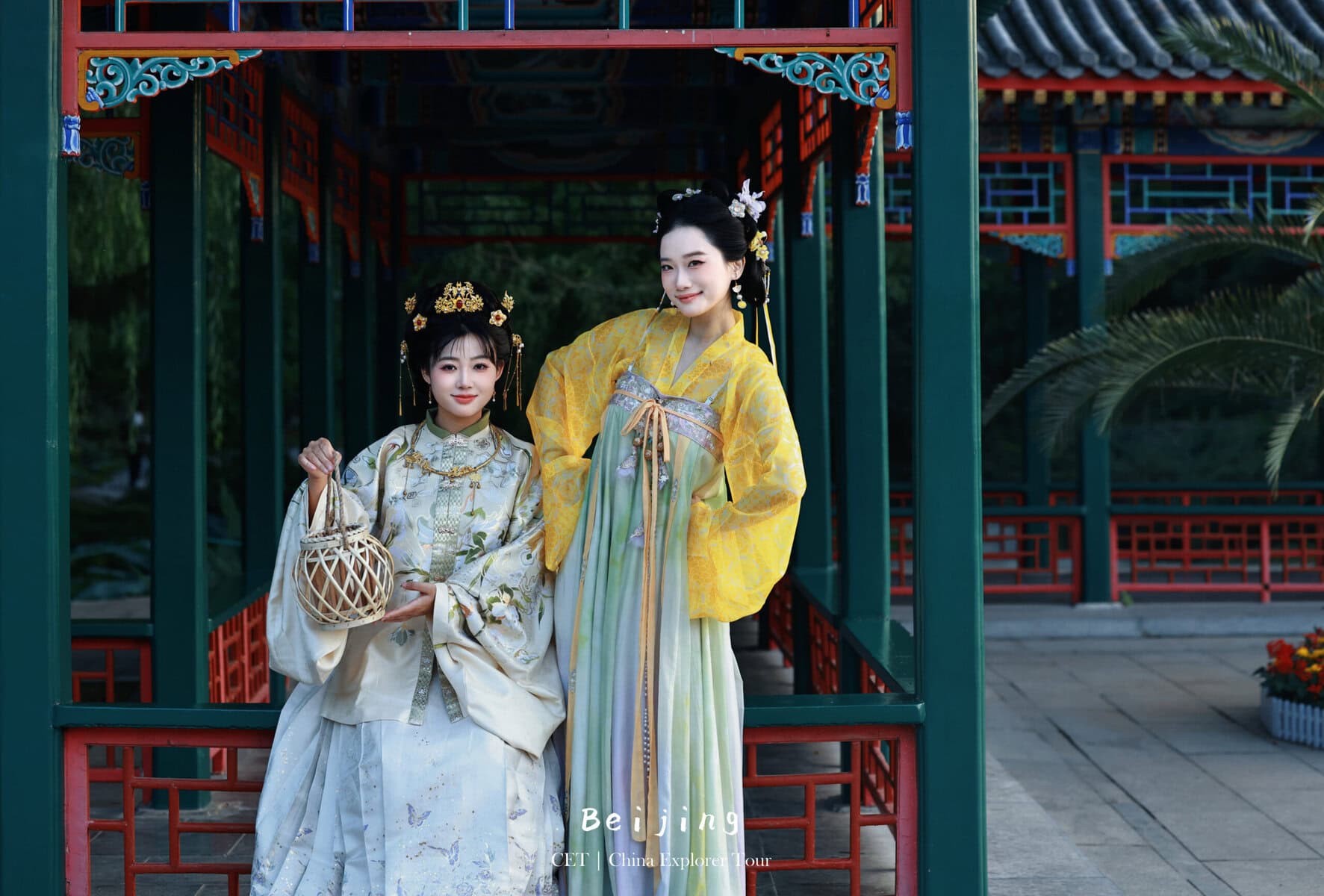 Hanfu photoshoot, the forbidden city, beijing, chinatravel, Two women in elaborate Hanfu dresses pose in a green and red Chinese pavilion; one holds a lattice lantern in front.