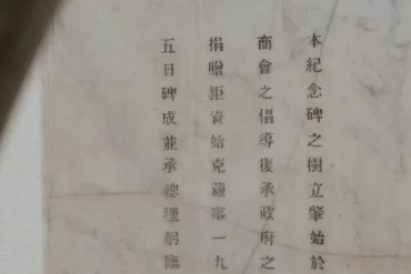 Stone marble memorial plaque with vertical Chinese text inscribed in neat columns, partially shadowed on the left.