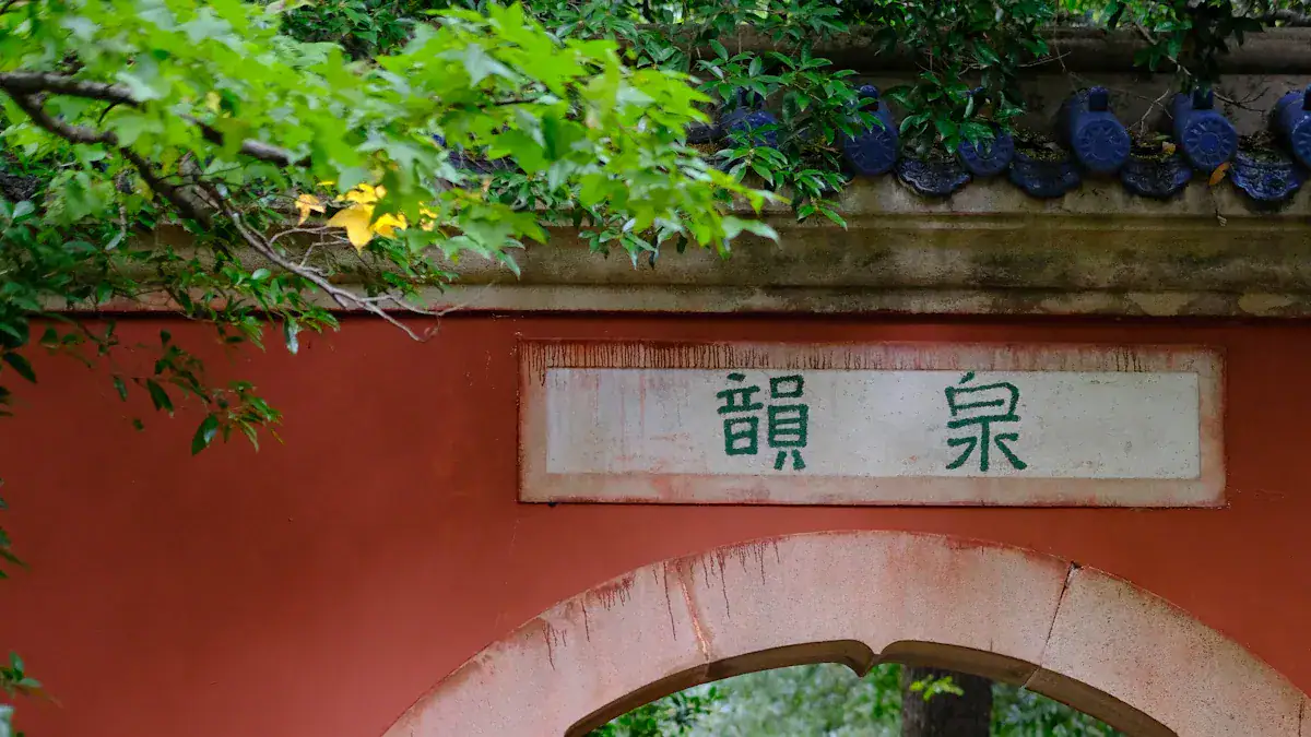 Wuhou Shrine,Chengdu,Chinatour White plaque with green Chinese characters 龍泉 on a red wall above a rounded arch, surrounded by green foliage.