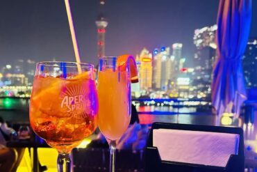 Shanghai Bar Rouge,Shanghai,Chinatour Two cocktails on a rooftop bar at night with a glowing city skyline in the background.