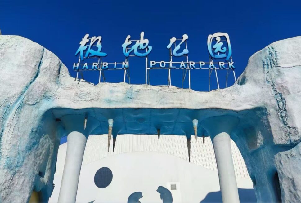 Harbin Polarland,Harbin,Chinatour Entrance to Harbin Polar Park with an icy blue arch and a blue sign reading 'Harbin Polar Park' against a clear sky.