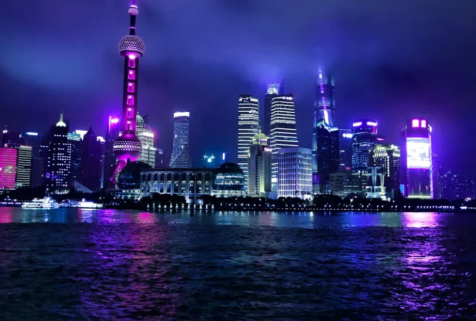 Shanghai skyline at night with the Oriental Pearl Tower lit in purple and water reflections nearby