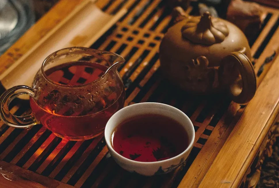 Chengdu's Best Tea House,Chengdu,Chinatour Glass teapot with red tea, white cup, and a brown ceramic teapot on a wooden tray.