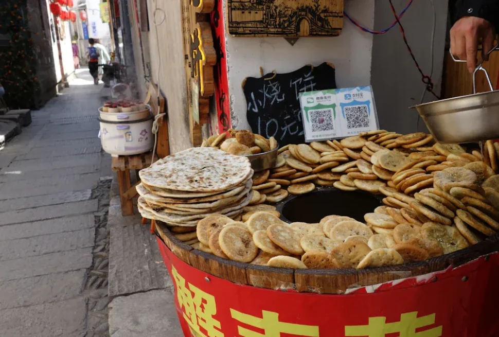 Roujiamo,Xi`an,Chinatour Street food stall with a circular pan surrounded by dozens of flatbreads in a busy alley.