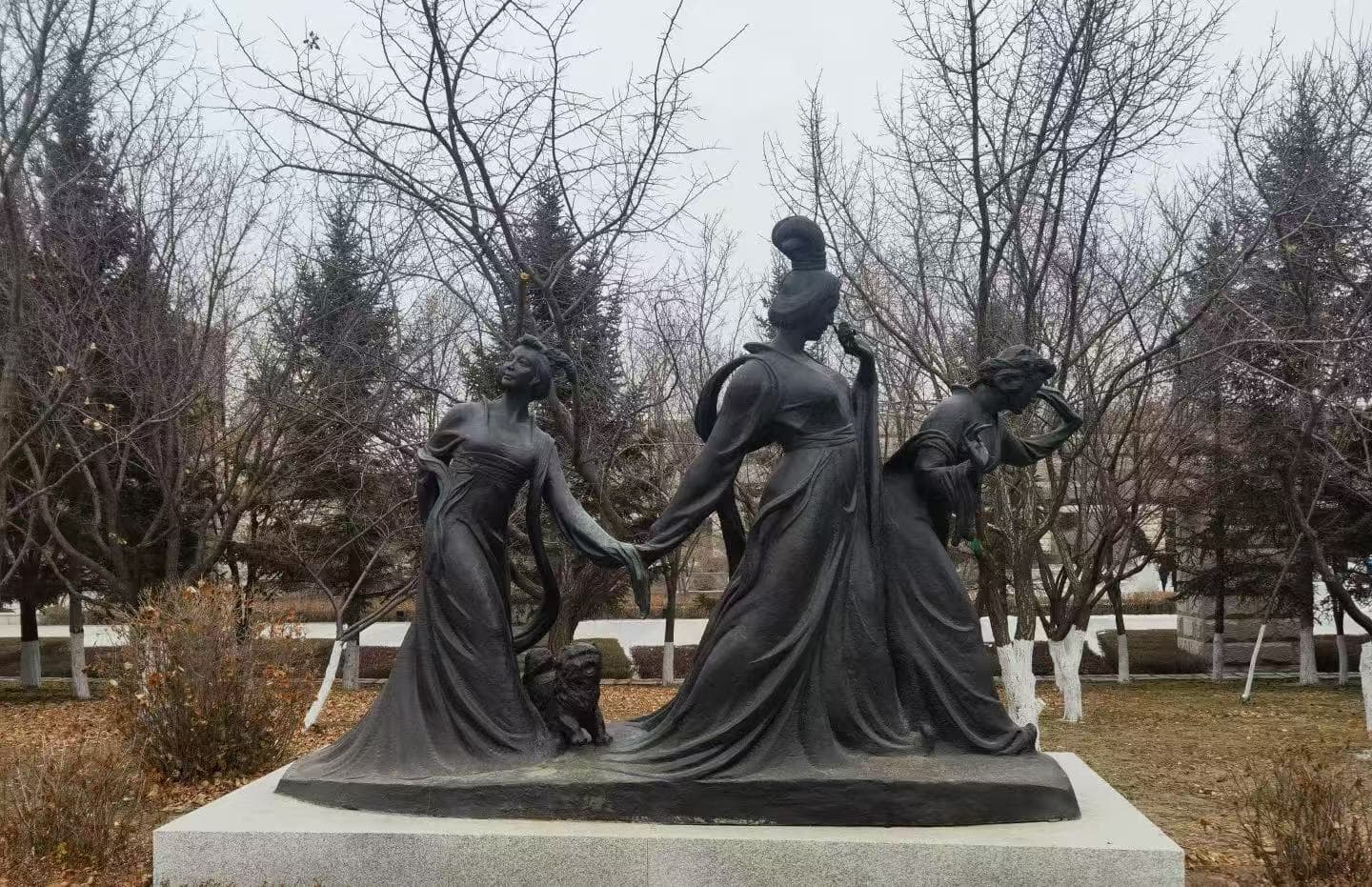 Changchun World Sculpture Park,Changchun,Chinatour Bronze sculpture of three figures in flowing robes on a stone pedestal in a park.